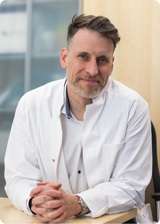 Porträt von Dr. Arne Ebermann an seinem Schreibtisch in der Ordination